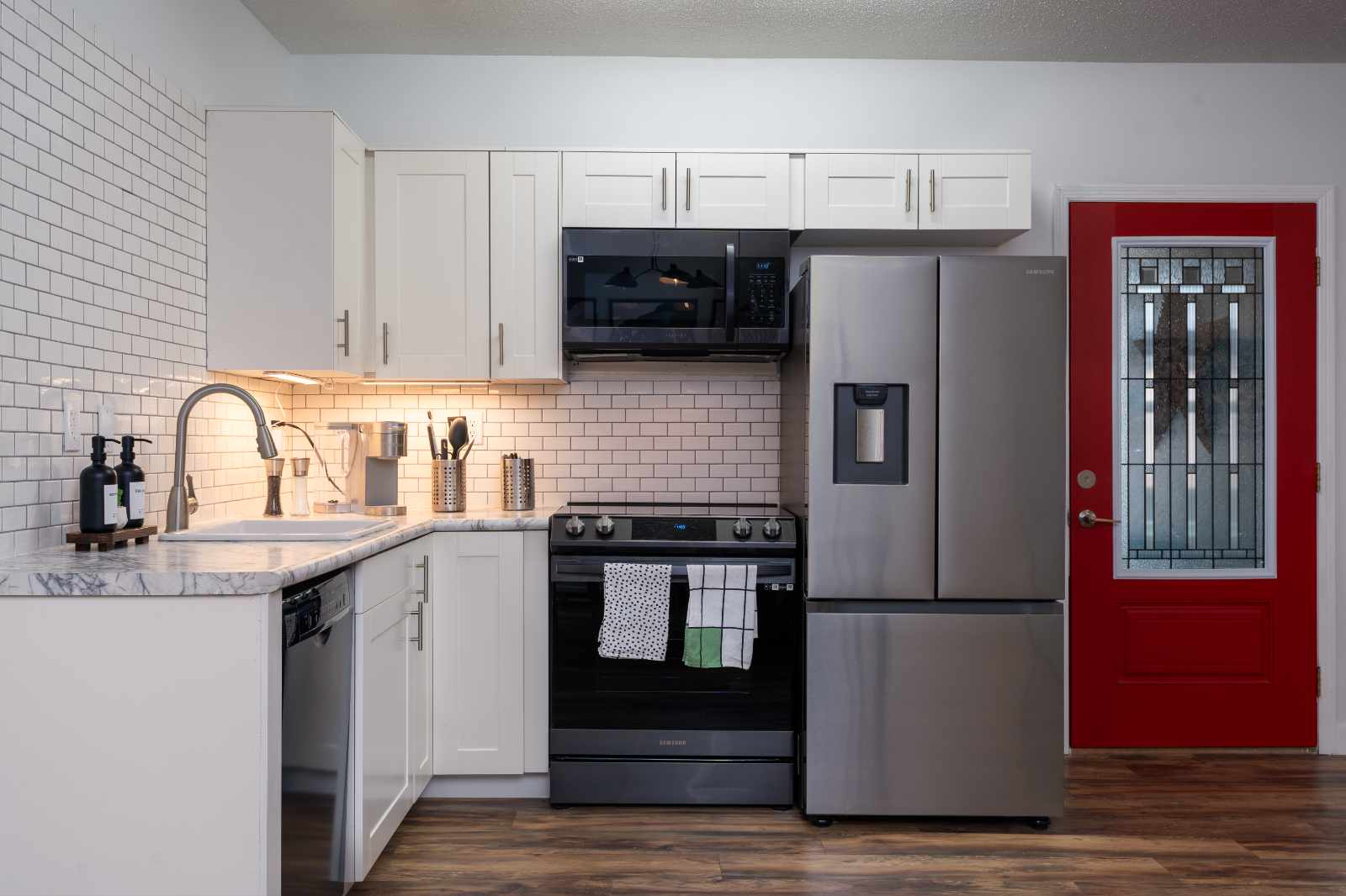 Kitchen with white cabinets and red door
